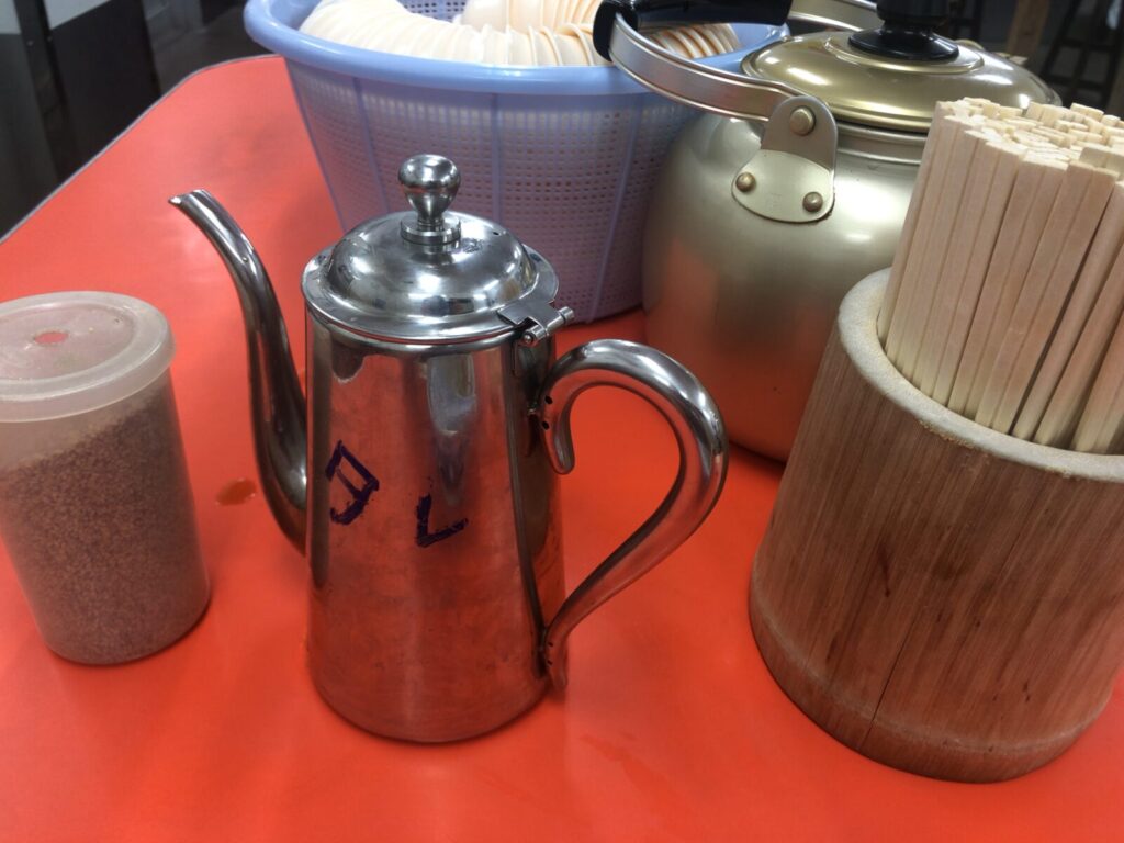 red pickled ginger, ramen sauce, sesame seeds, and a tea kettle on the table