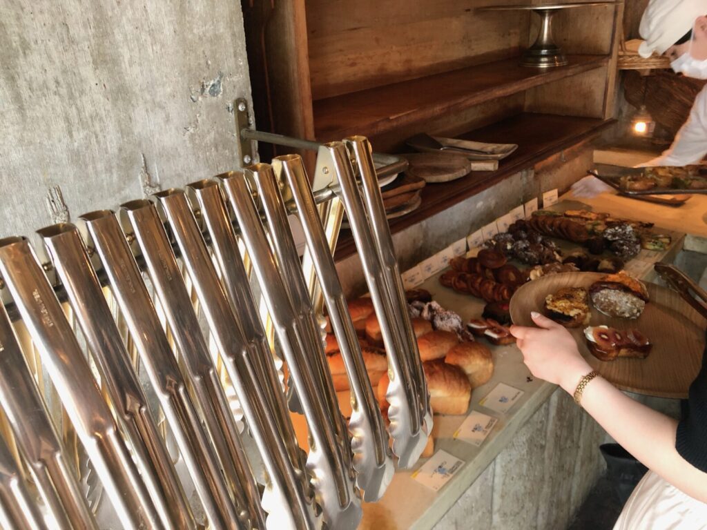 Using tongs to pick up bread and place it on a tray